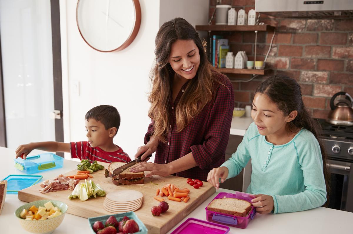Children helping to pack their lunch at home in the kitchen