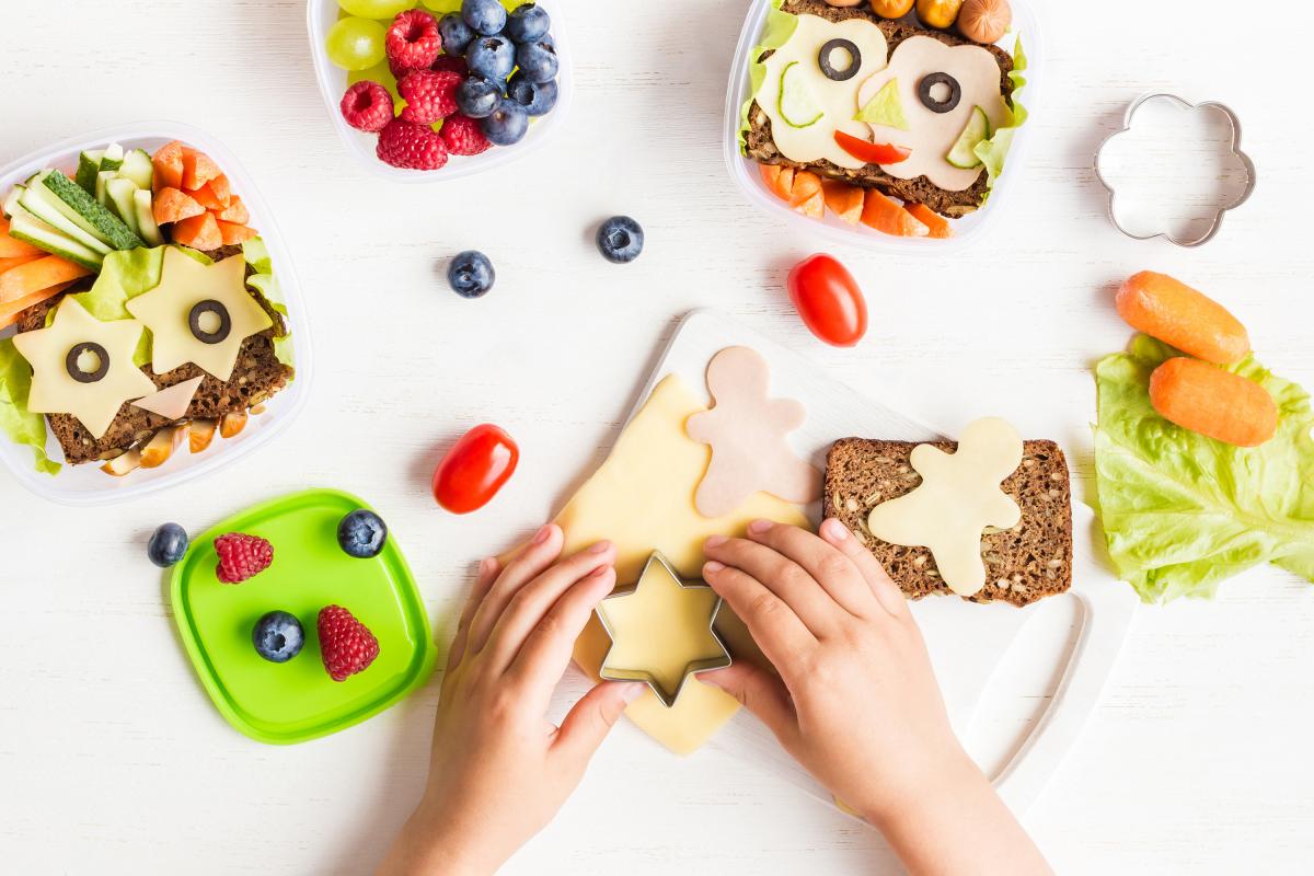 Child's hands making fun shapes out of their food for school lunch.