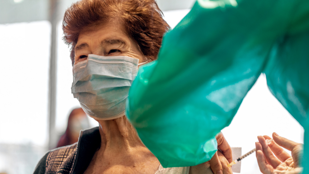 Older adult receiving vaccine wearing a mask