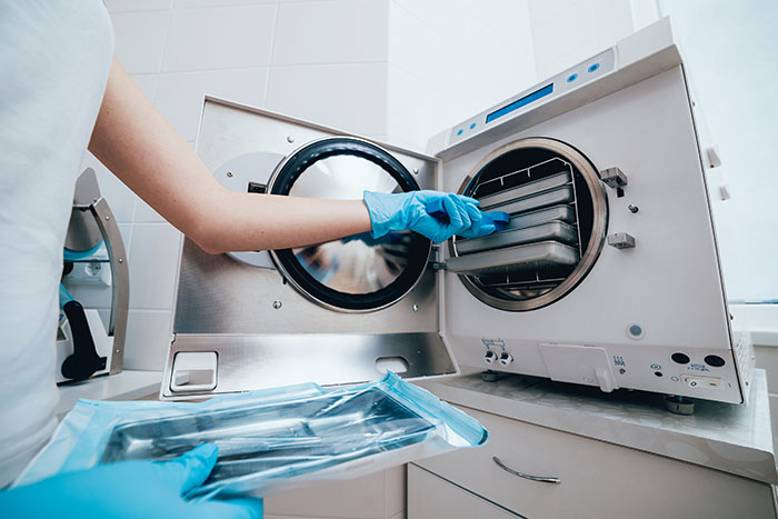 health care working putting tools into an autoclave