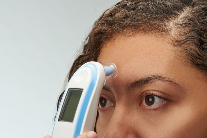 Lady taking her own temperature on her forehead