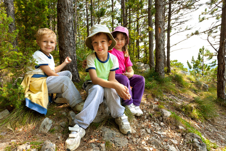 Three school age kids in a forest