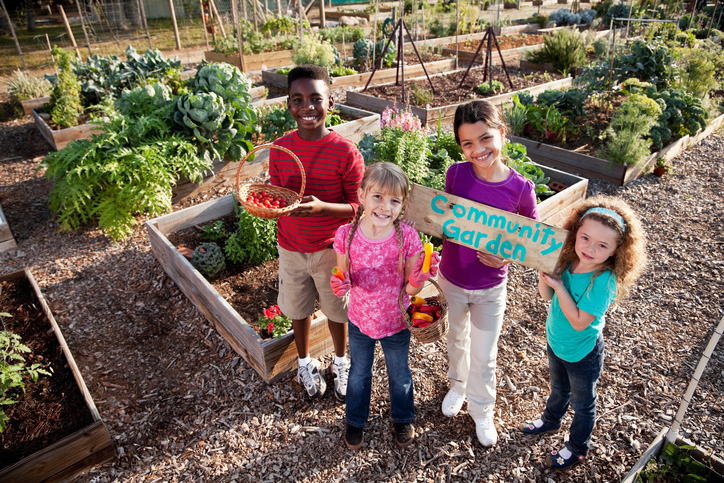 4 multi-cultural kids standing in a community garden