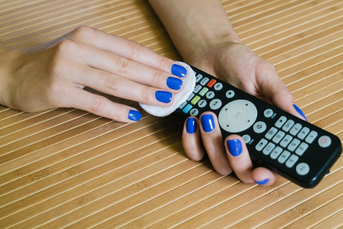 Hands cleaning television remote