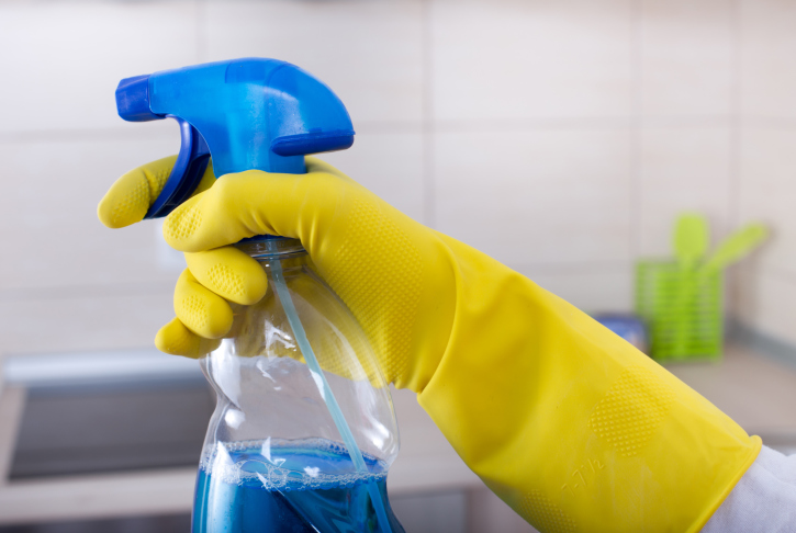 Hand in rubber glove holding spray bottle