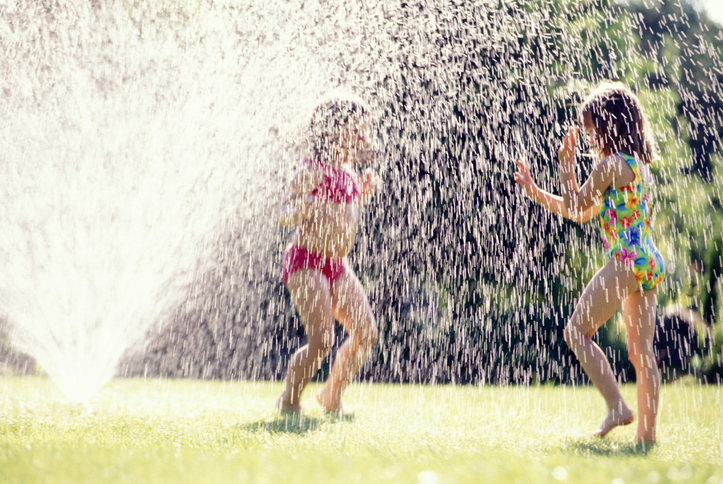 Two girls running through sprinkler