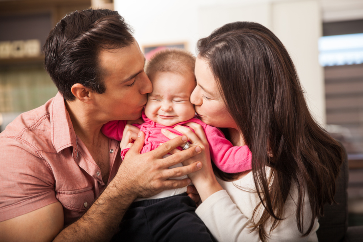 Parents kissing baby