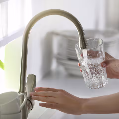 Woman running tap water into glass in kitchen