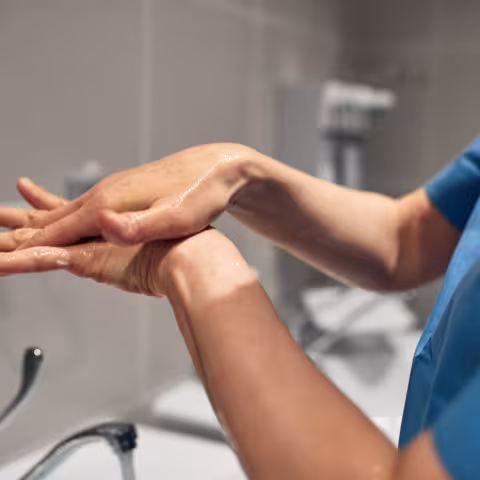 Close-up of a PSW washing his hands using a disinfectant dispenser - stock photo