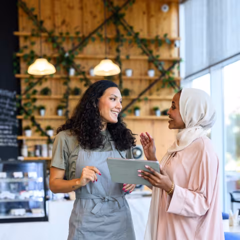 Two diverse women discussing small business strategy in a cafe 