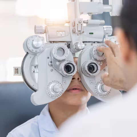 Boy doing eye test checking examination with optometrist