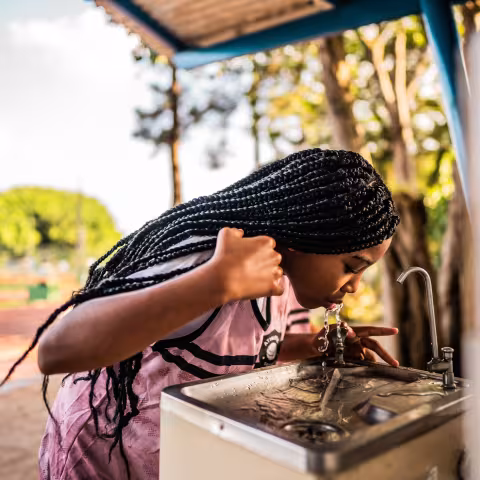 Girl drinking from water fountain outside
