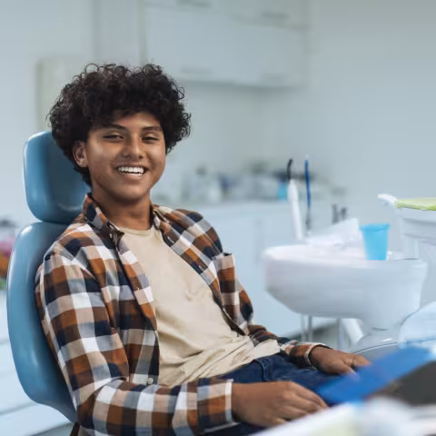 Smiling young teen boy sitting in a dental chair