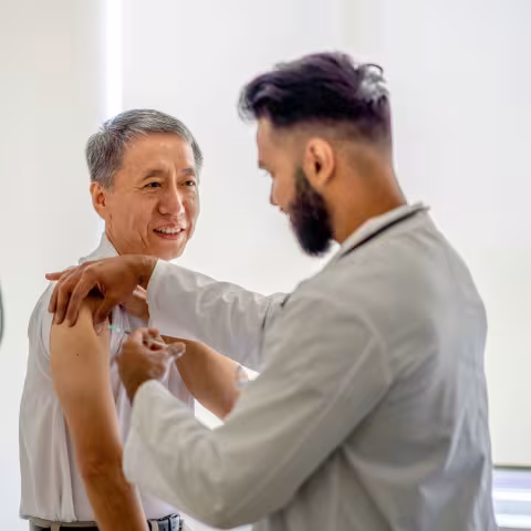 A male doctor administering a medical injection into a senior patient's arm.