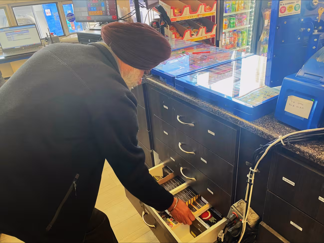 A public health inspector checks tobacco products behind the counter at a tobacco retailer.