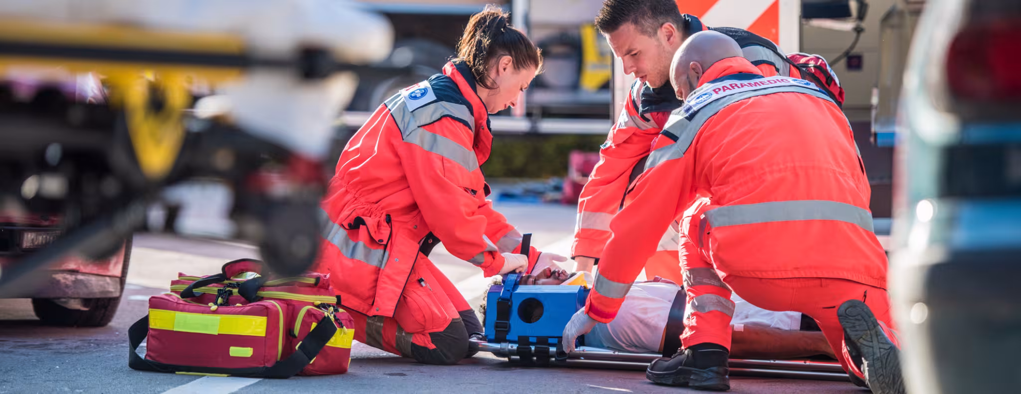 Paramedics providing first aid to man injured in car accident.