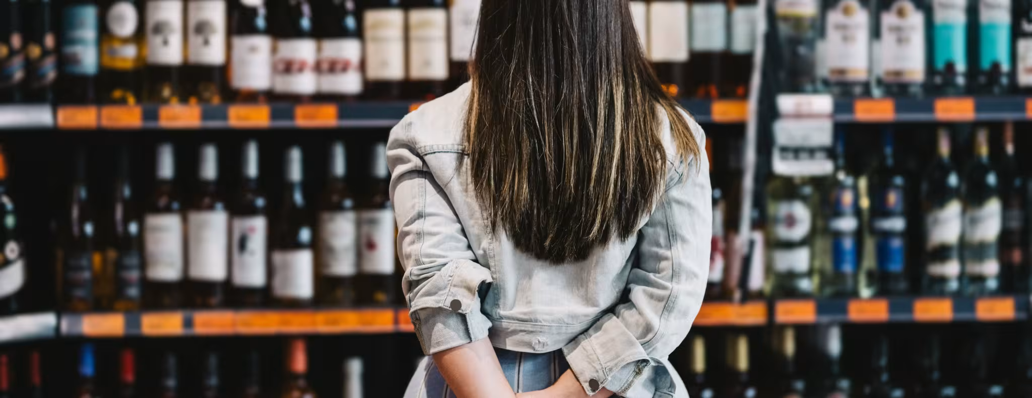 Woman customer looking at a rack of wine in supermarket