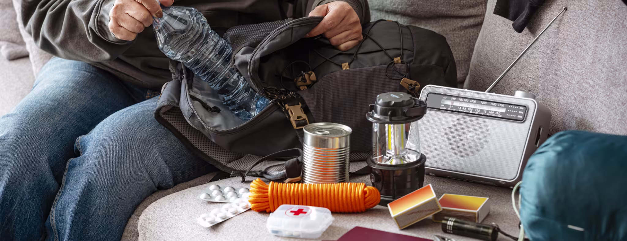 Woman filling emergency backpack with disaster emergency supplies