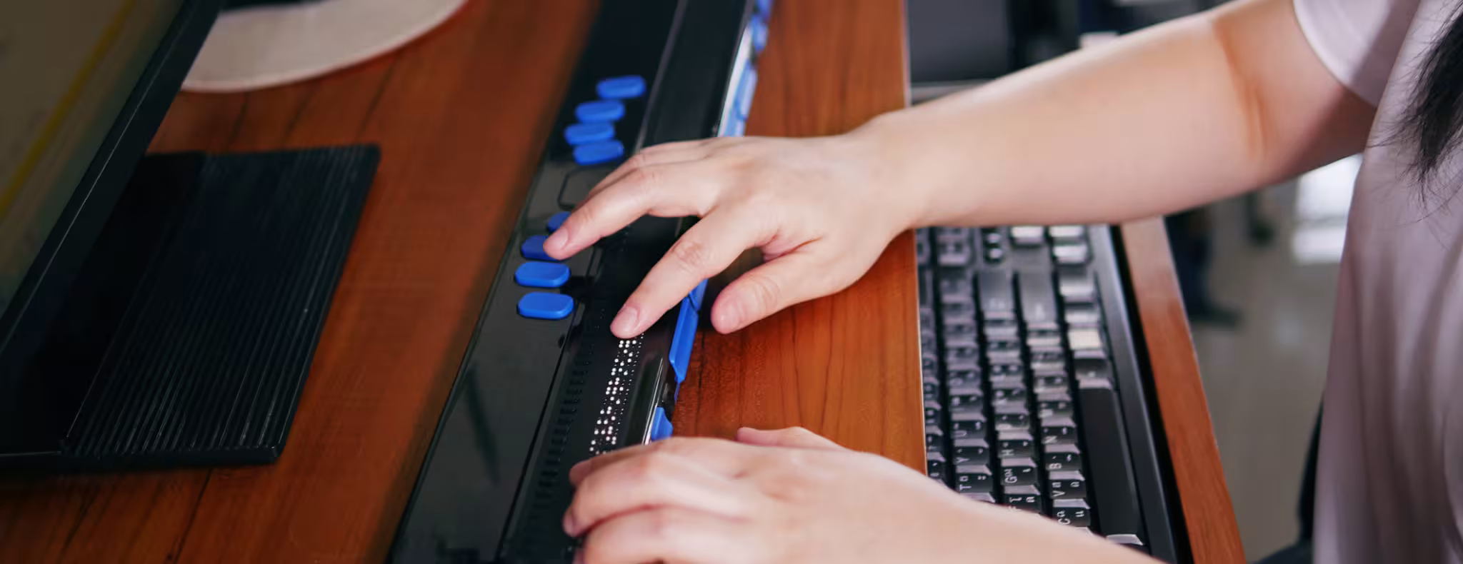 Person with blindness disability's hands using computer with braille display or braille terminal a technology assistive device for persons with visual impairment.