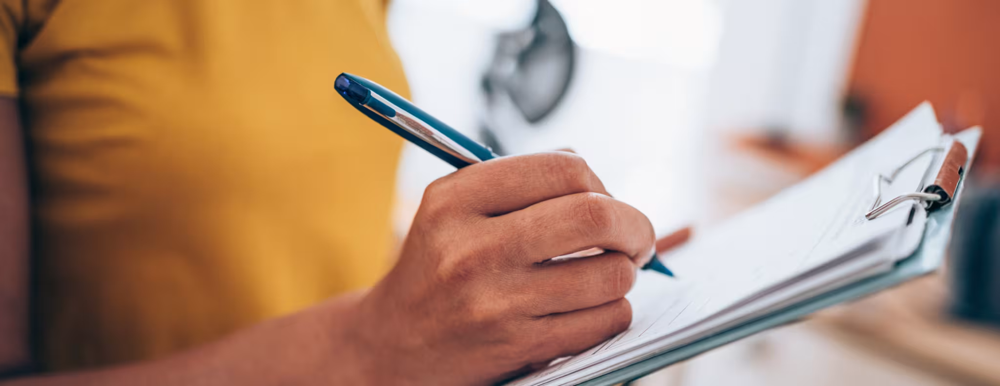 Woman hand writing on clipboard with a pen.