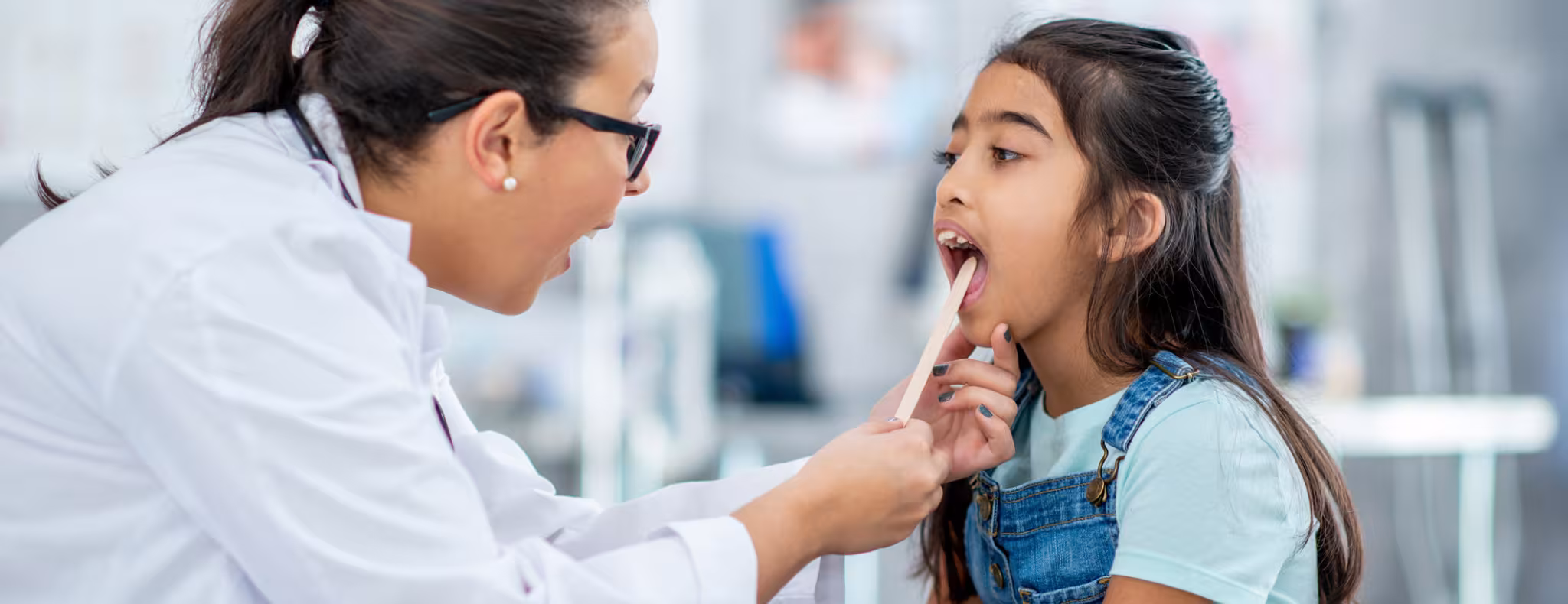A little girl of Middle Eastern decent, sits up on an exam table during a routine check-up. 