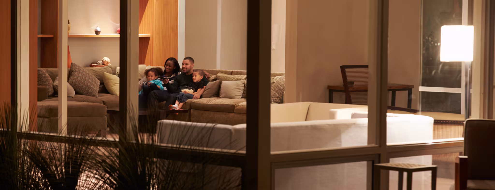 Family Watching TV At Home Viewed From Outside