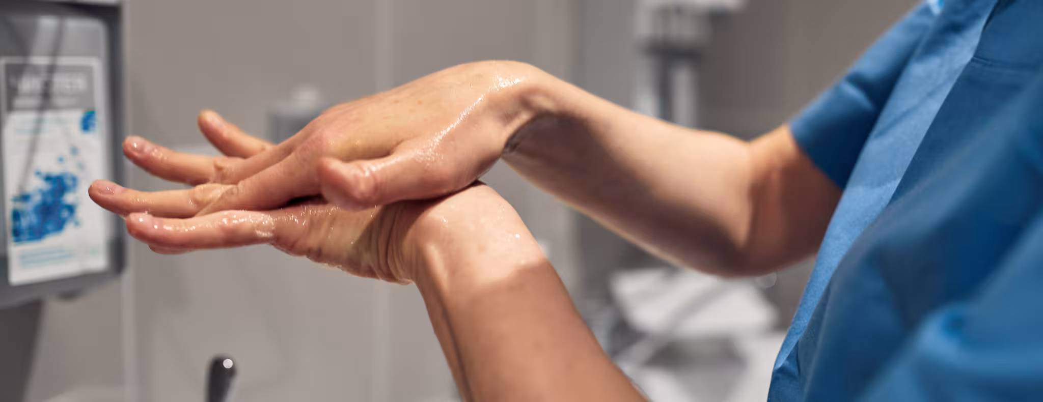 Close-up of a PSW washing his hands using a disinfectant dispenser - stock photo