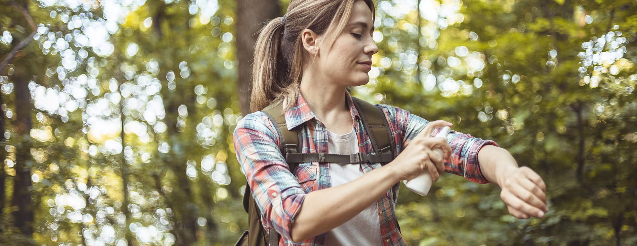 Woman Applying Insect Repellent Against Mosquito and Tick During Hike in Nature
