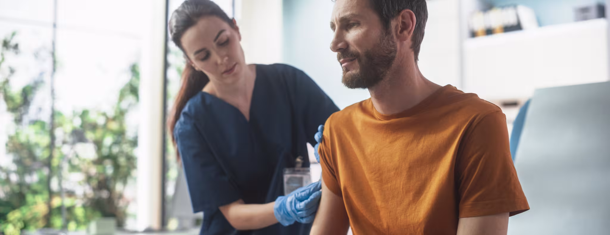 Happy Caucasian Man Sitting In The Chair In Bright Hospital And Getting His Hepatitis B Vaccine.