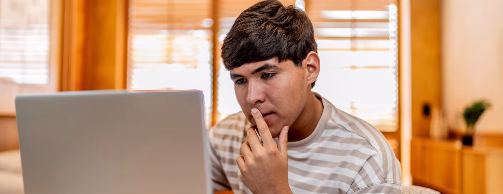 Teenage boy on laptop thinking