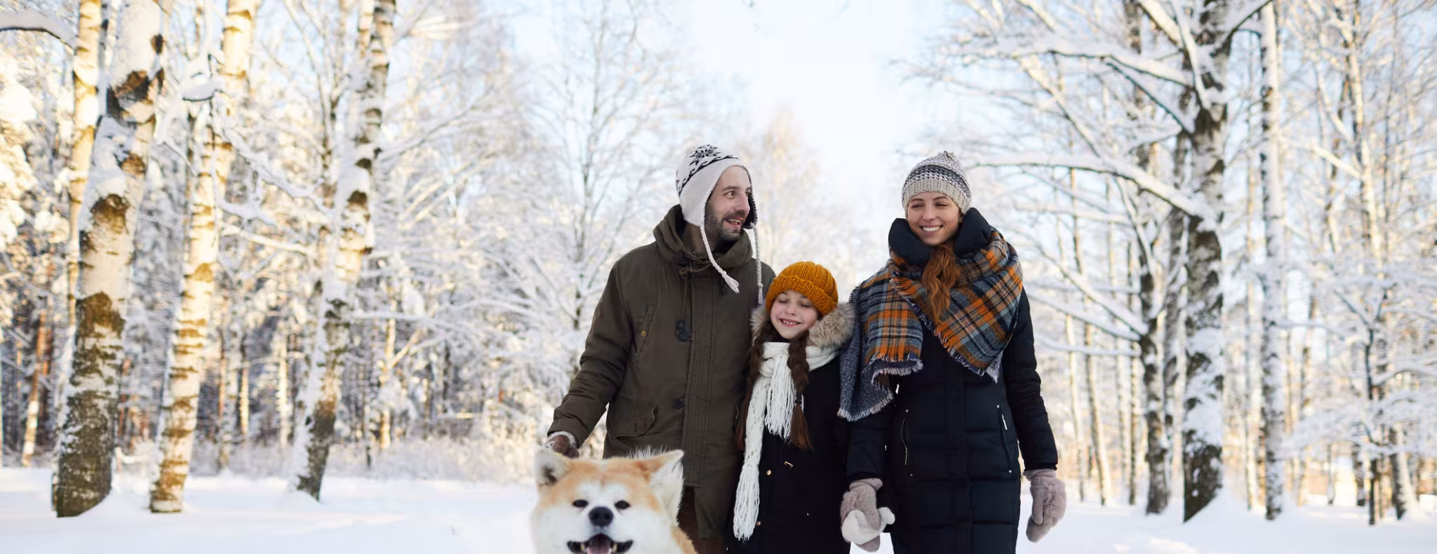 family walking in the woods with their dog in winter
