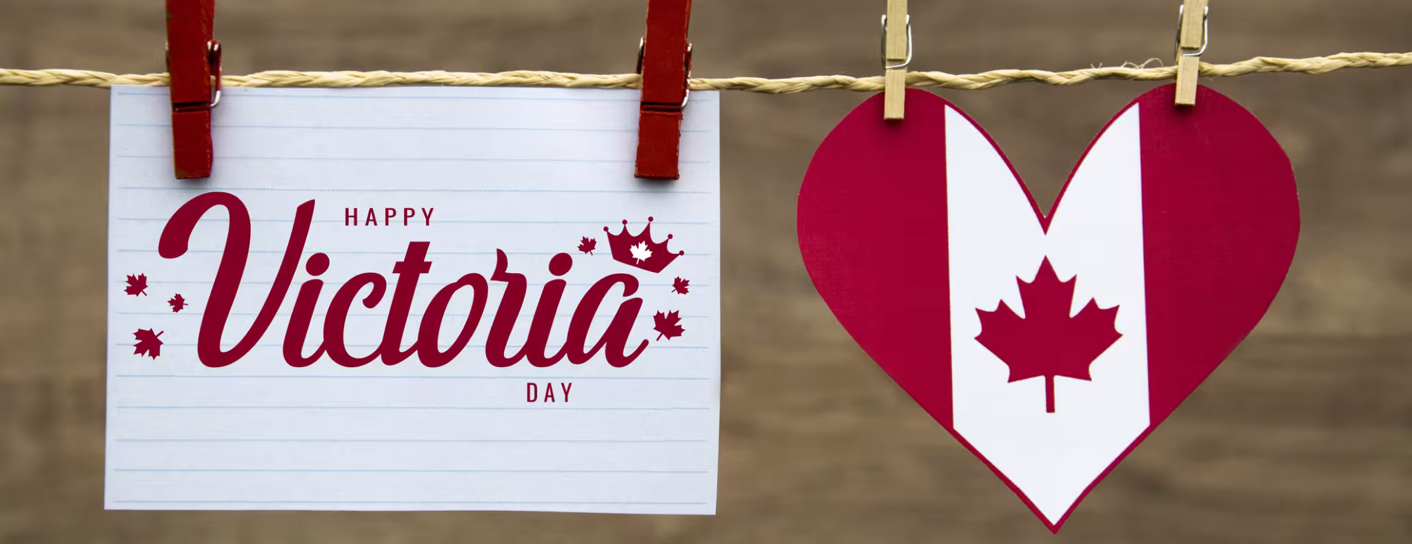Clothes line with a sign pinned to it that reads "Happy Victoria Day" and a Canadian flag heart beside it.