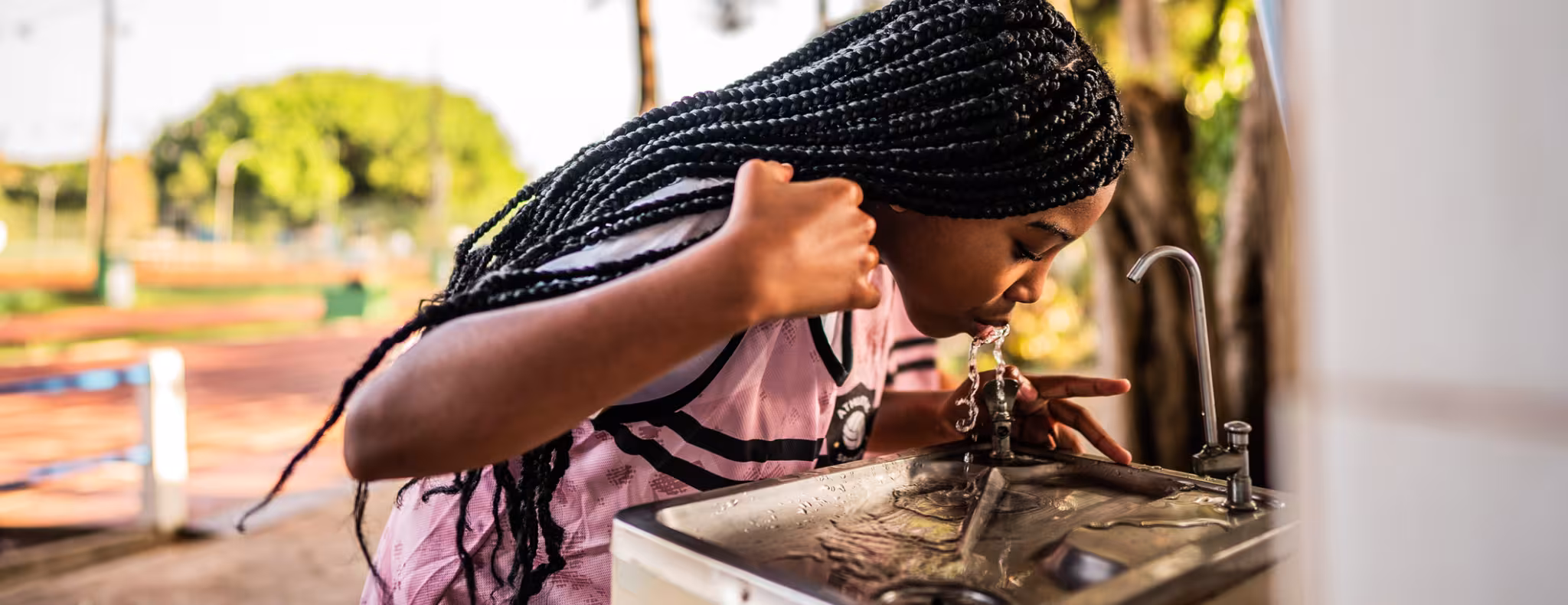 Girl drinking from water fountain outside