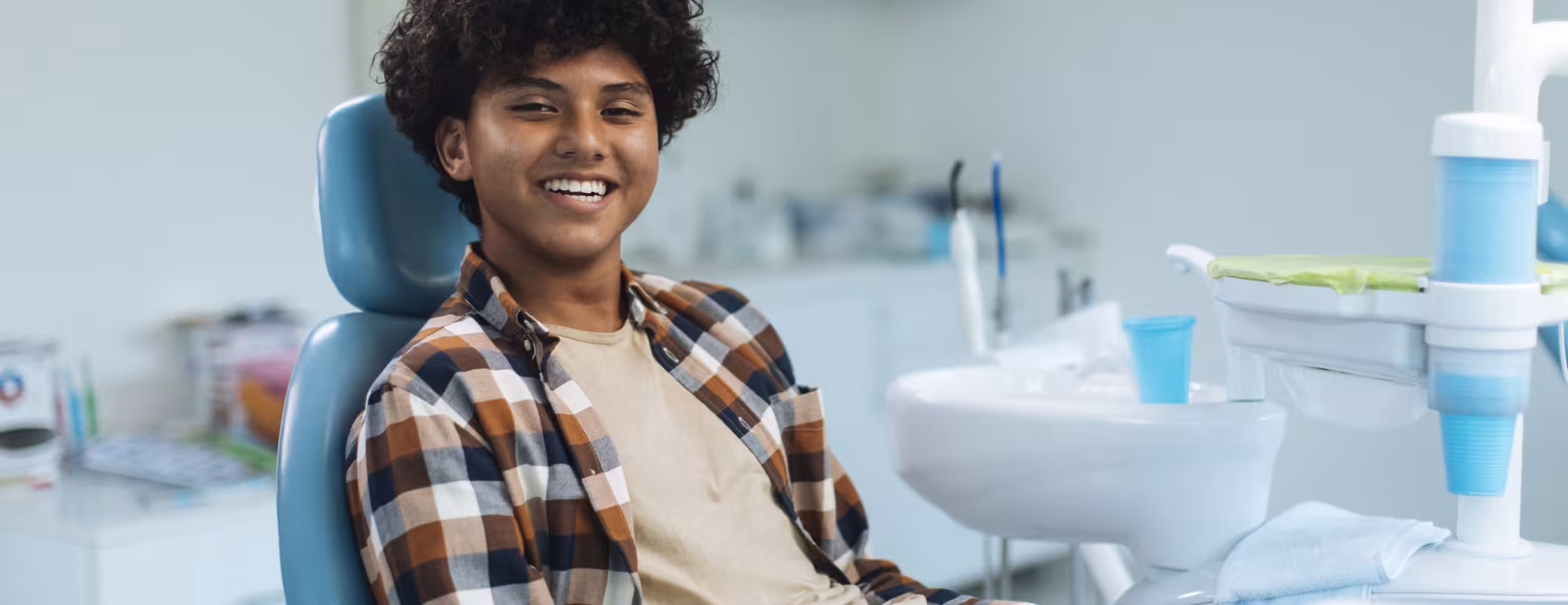 Smiling young teen boy sitting in a dental chair