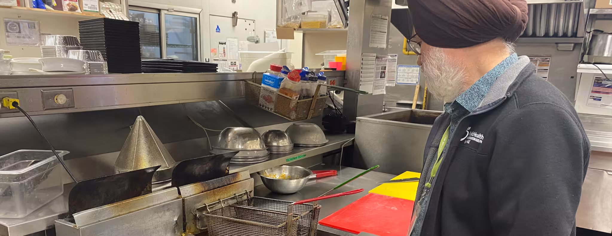 A public health inspector looks over deep fryers in a restaurant kitchen.